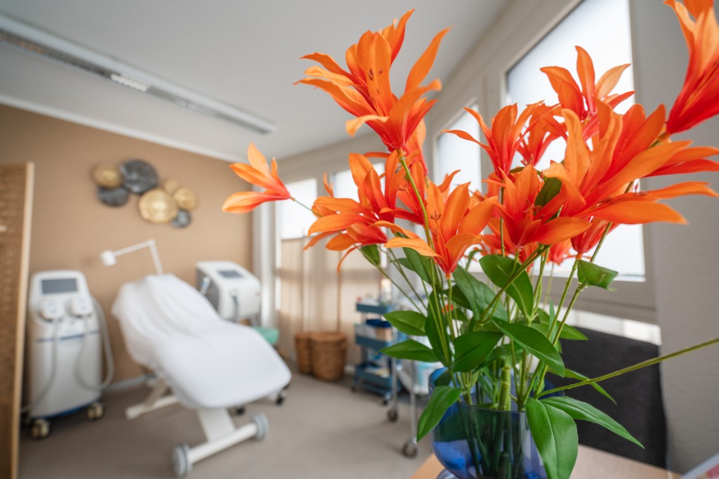 Behandlungsraum mit orangen Blumen und Liege